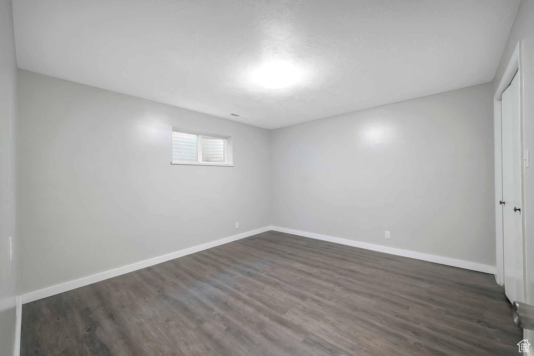 Unfurnished room with baseboards and dark wood-style floors