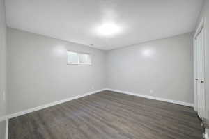 Unfurnished room with baseboards and dark wood-style floors