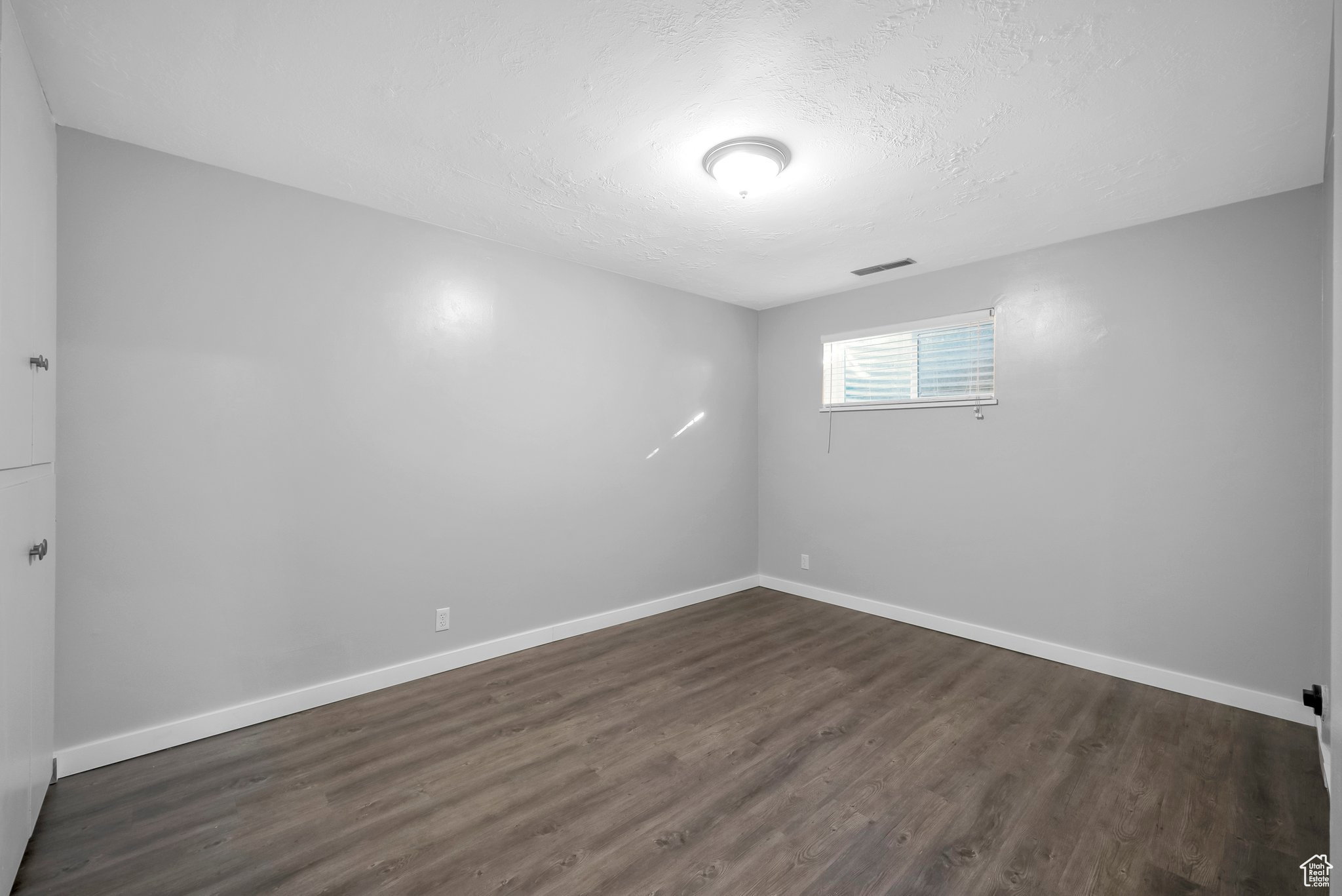 Unfurnished room with dark wood-style flooring and a textured ceiling