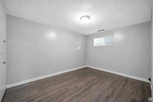 Unfurnished room with dark wood-style flooring and a textured ceiling