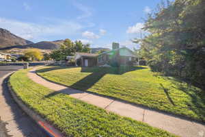 View of front of property with a mountain view, a chimney, a front lawn, and brick siding