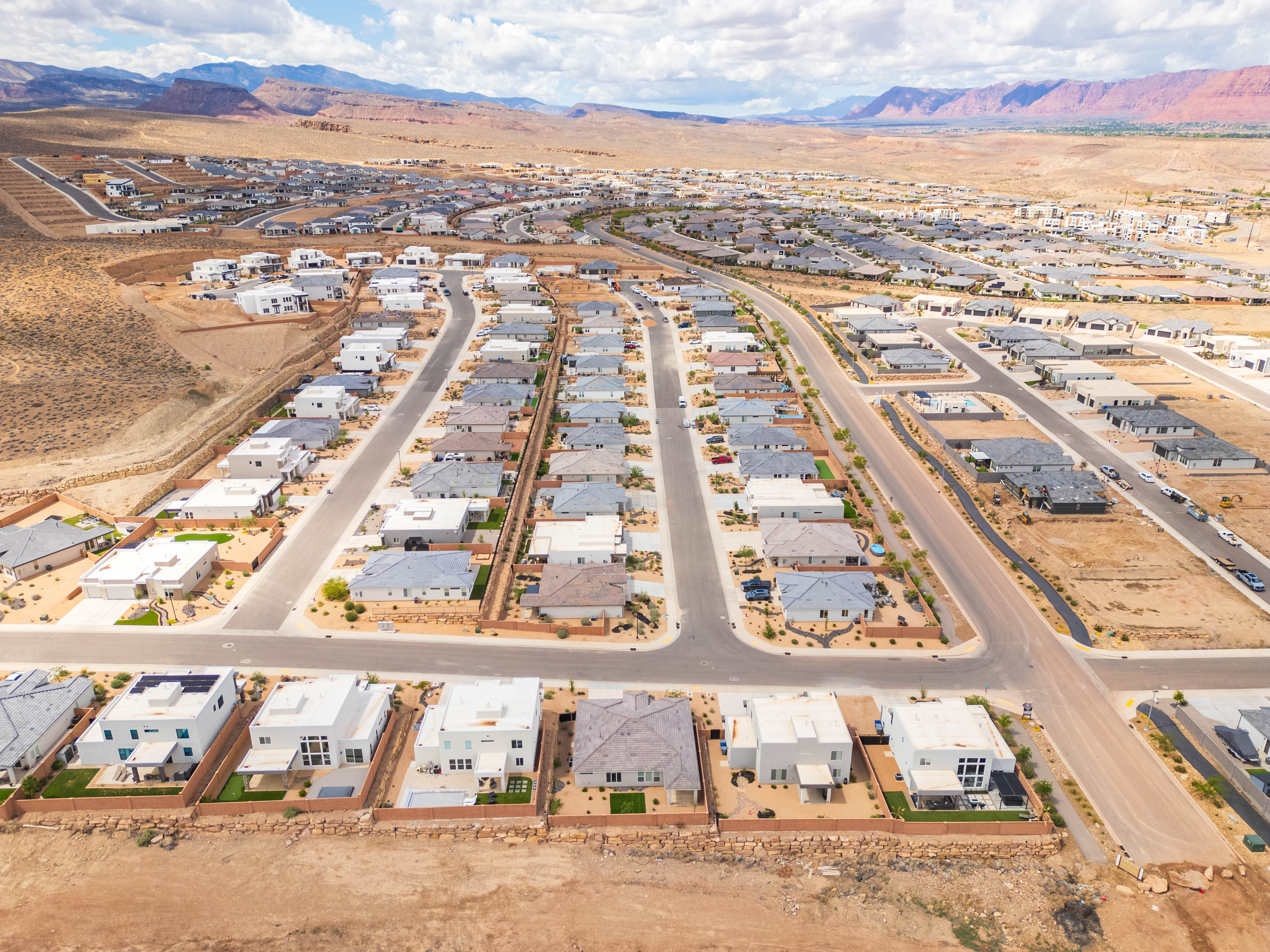 Aerial view of property and surrounding area featuring nearby suburban area and a mountainous background
