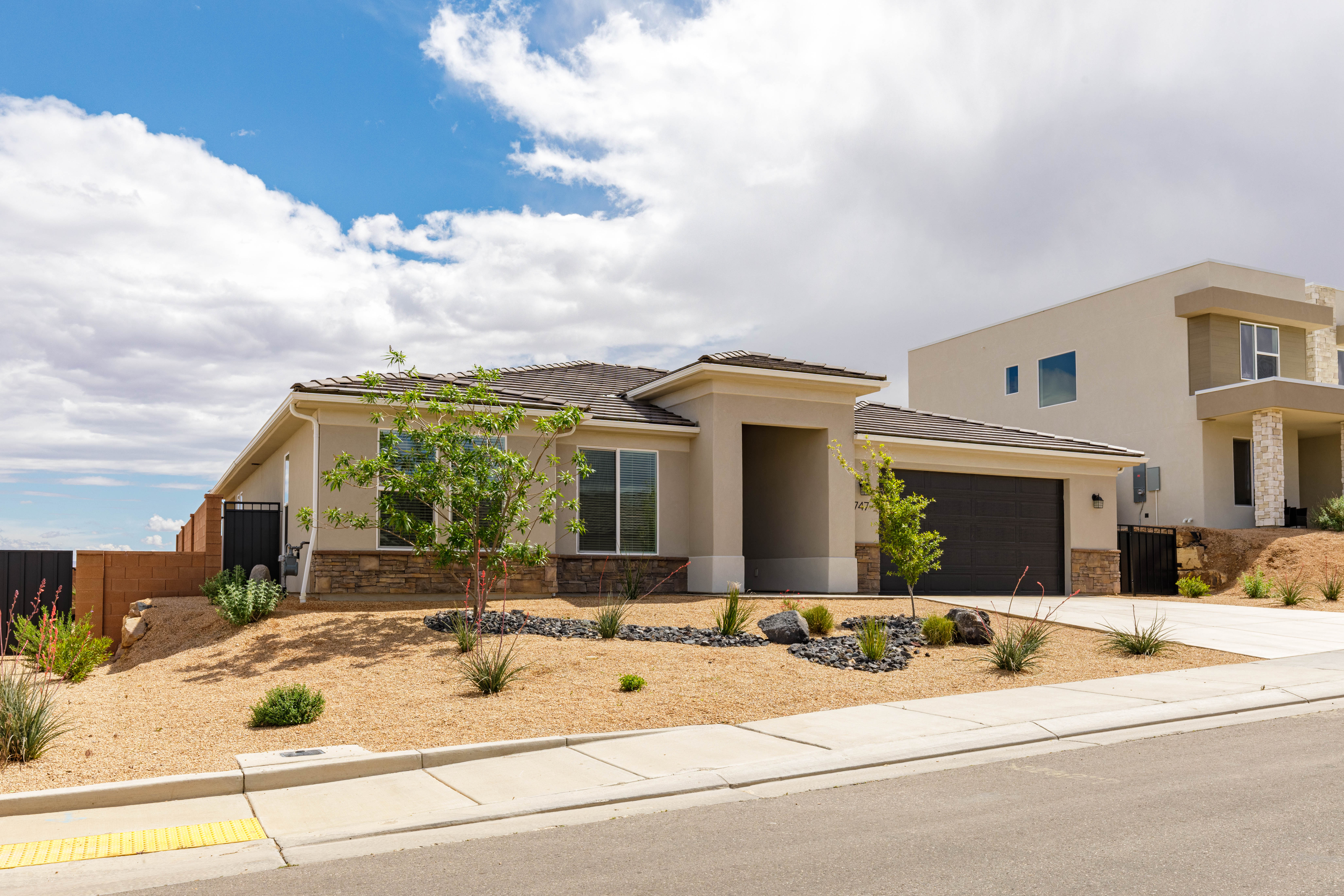 View of front facade featuring stone siding, stucco siding, a garage, and driveway