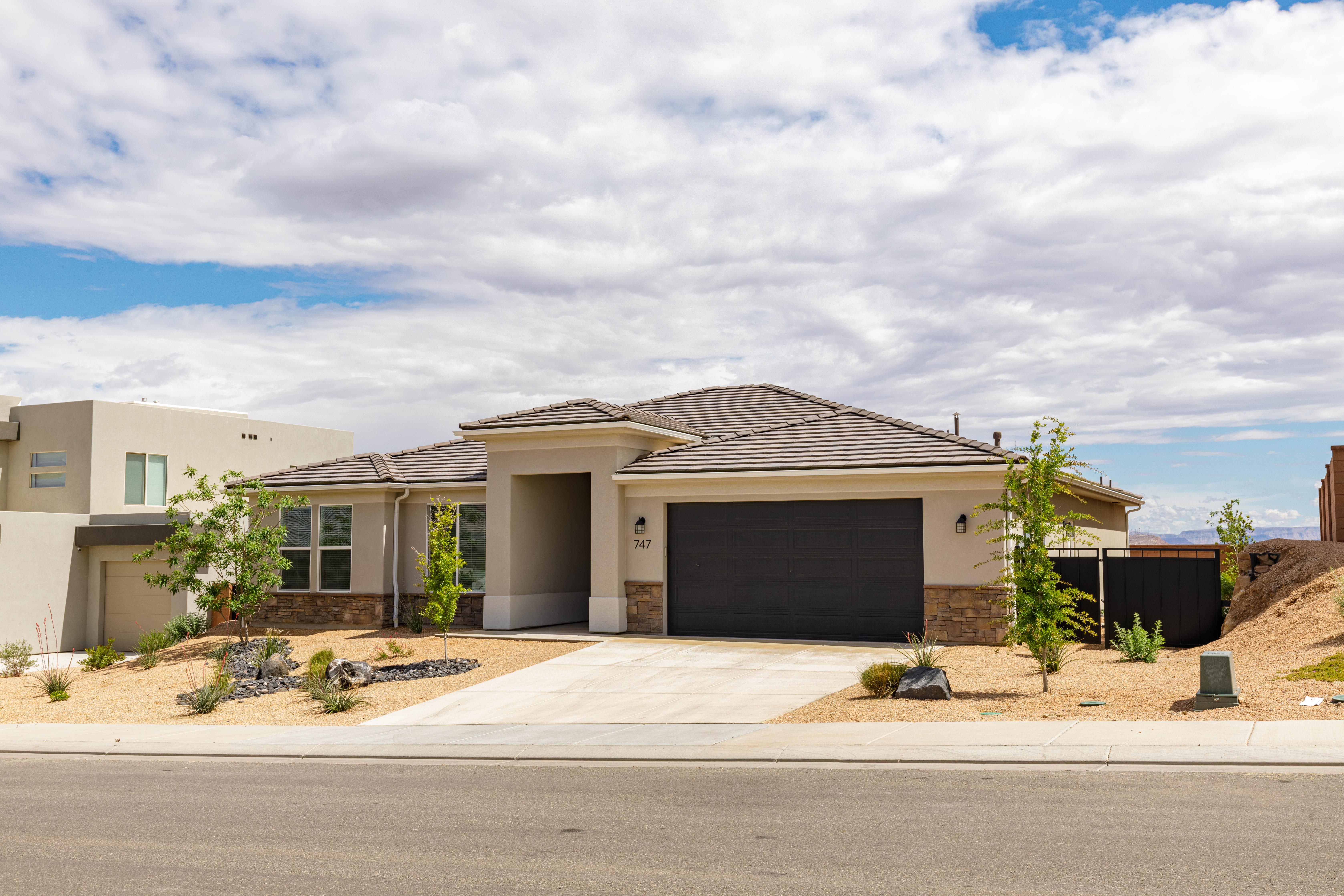 Prairie-style home featuring stone siding, stucco siding, an attached garage, and driveway