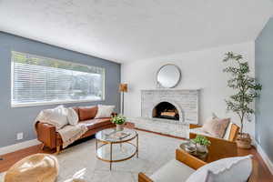 Living room with wood finished floors, natural light,  and a fireplace