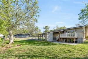 Back of house featuring mature trees, a patio area, and a deck