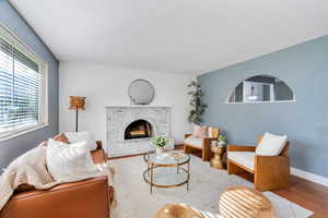 Living room featuring wood finished floors, natural light, and a brick fireplace