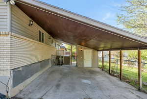 View of parking featuring a carport and a shed