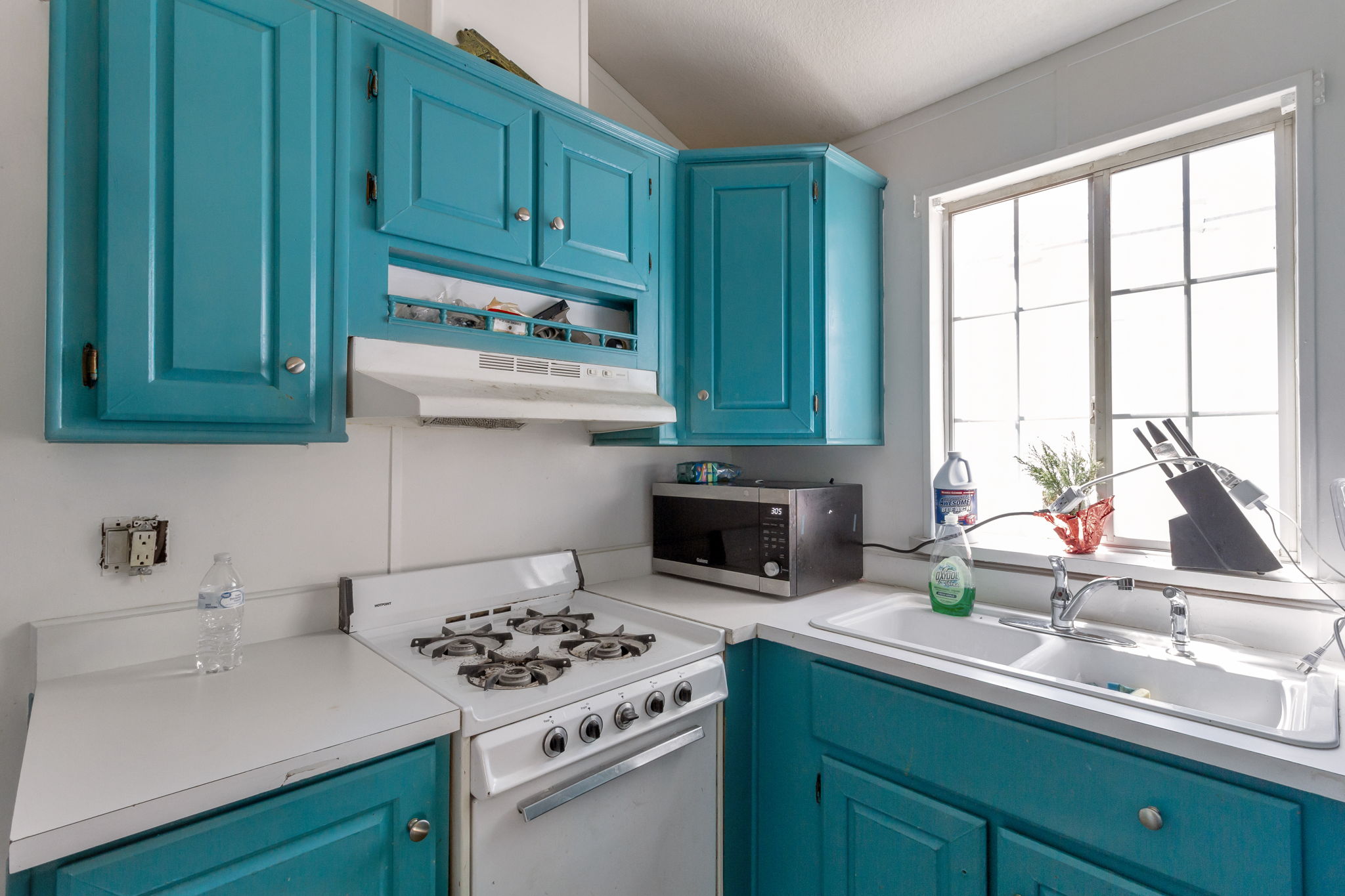 Kitchen with blue cabinets, white range with gas stovetop, and light countertops
