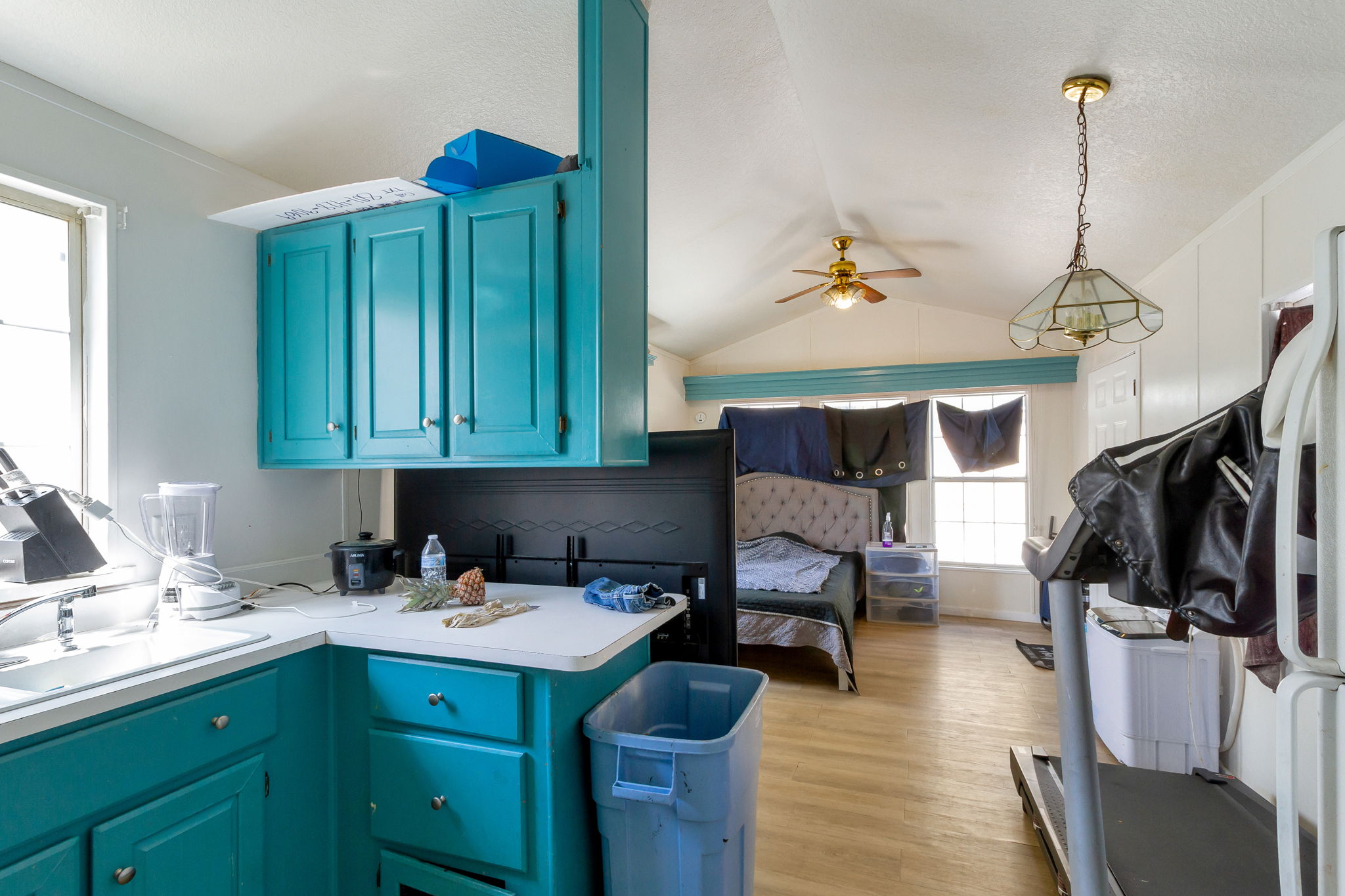 Kitchen featuring light countertops, blue cabinets, light wood-style flooring, ceiling fan, and freestanding refrigerator