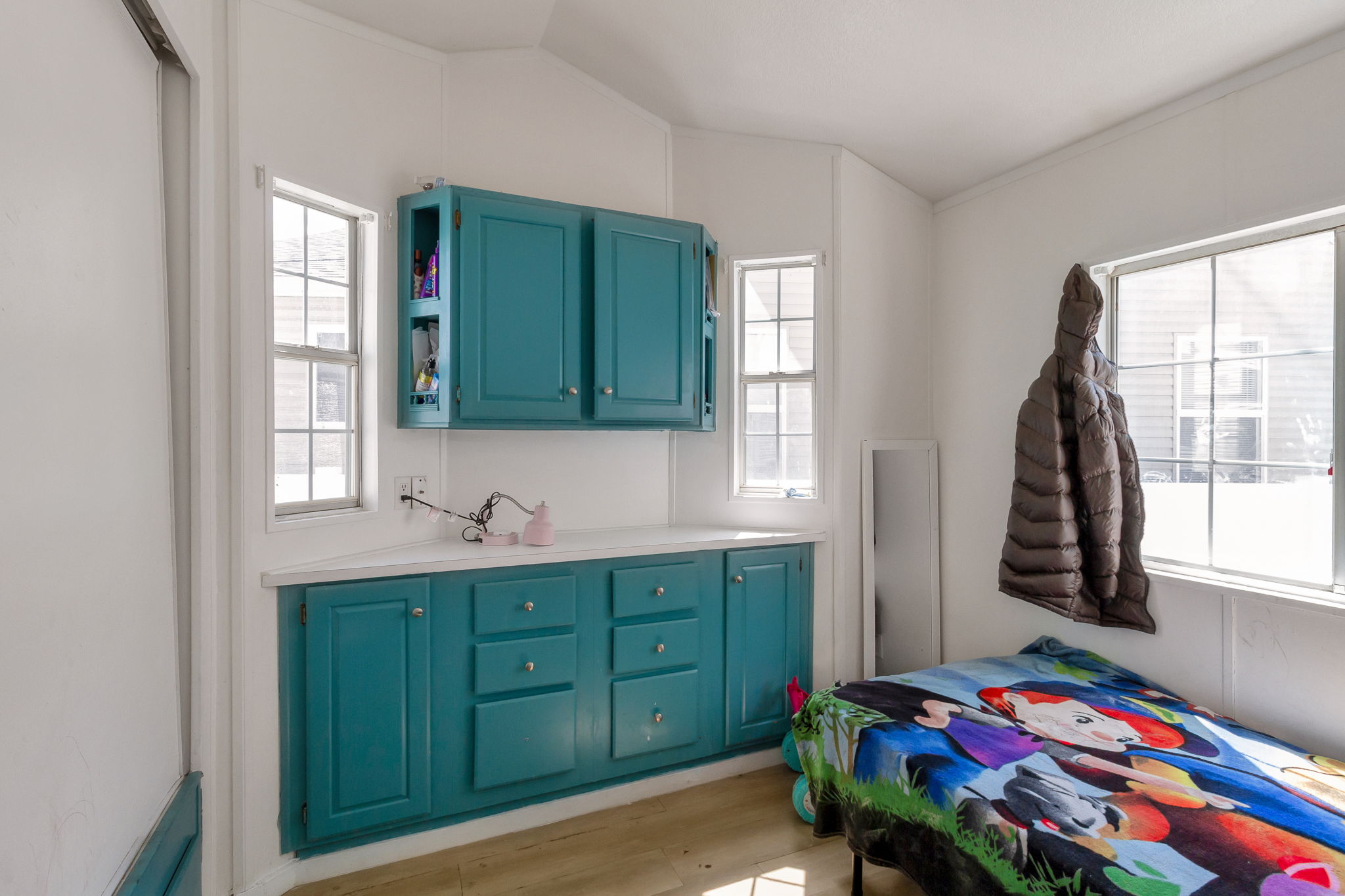 Bedroom with light wood-type flooring, multiple windows, and lofted ceiling
