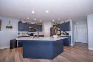 Kitchen with tasteful backsplash, stainless steel appliances, an island with sink, dark wood-style floors, and recessed lighting