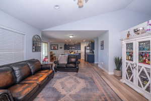 Living room featuring vaulted ceiling, light wood-type flooring, a ceiling fan, and recessed lighting