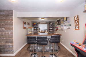 Indoor dry bar featuring butcher block countertops, dark colored carpet, and open shelves