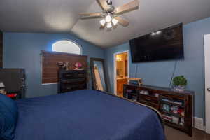 Bedroom featuring ceiling fan, dark colored carpet, and ensuite bathroom