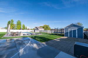 Fenced backyard with a shed, a patio area, outdoor dining area, and a trampoline
