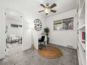 Home office with light colored carpet and ceiling fan