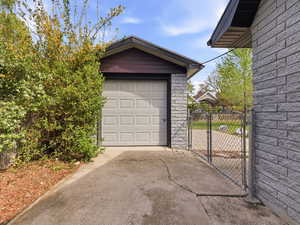 Detached garage featuring a gate and concrete driveway