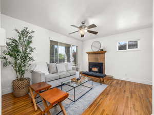 Family area with hardwood / wood-style floors, a ceiling fan, and a tile fireplace