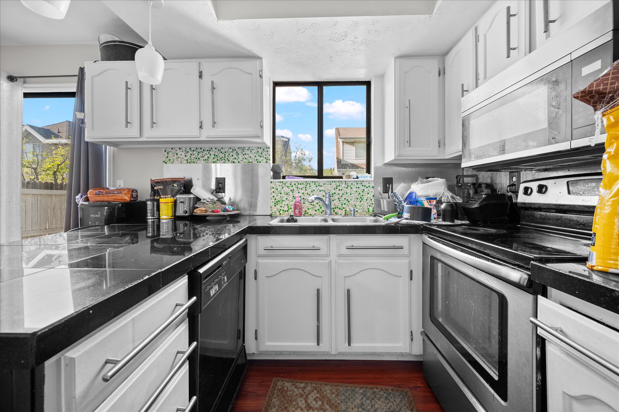 Kitchen featuring stainless steel range with electric cooktop, white cabinets, and tile counters