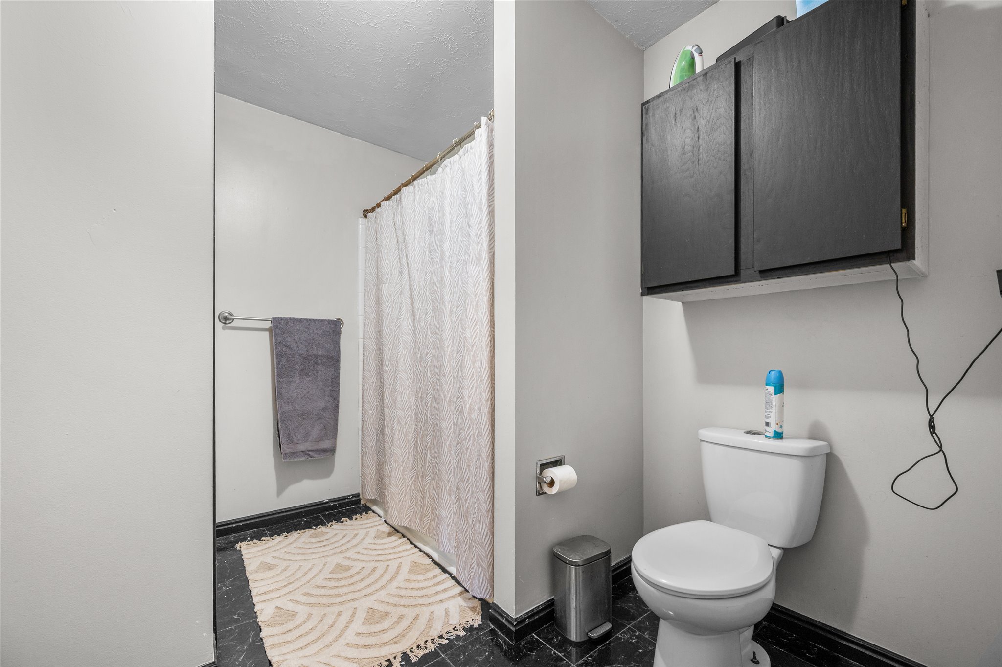 Full bath featuring curtained shower and a textured ceiling