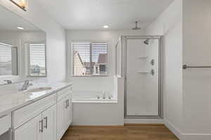 Primary ensuite bathroom featuring LVP flooring, vanity with white cabinets, upgraded quartz countertops, and makeup counter, separate soaker tub and shower