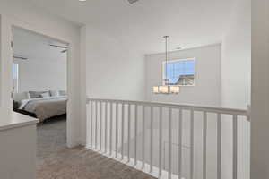 Hallway and stairwell with light colored carpet and plenty of natural light