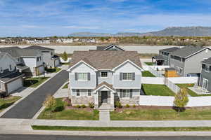 Exterior view of home featuring light Hardie board siding, stone, covered front porch, and a side-load garage.