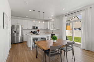 Kitchen with high ceilings, white cabinetry, spacious island, upgraded quartz countertops, LVP flooring, and stainless steel appliances