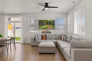 Open concept living room with high ceilings, LVP flooring, designer lighting, and natural light