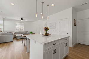 Open concept main floor layout featuring kitchen with high ceilings, white cabinetry, spacious island, upgraded quartz countertops, LVP flooring