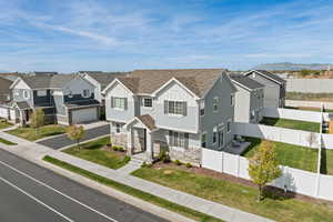 Exterior view of home featuring light Hardie board siding, stone, covered front porch, and a side-load garage.