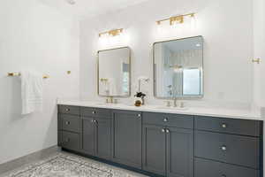 Bathroom featuring double vanity, a shower stall, and light tile patterned floors