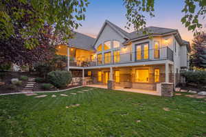 Rear view of house with a patio area, stucco siding, stone siding, and a yard