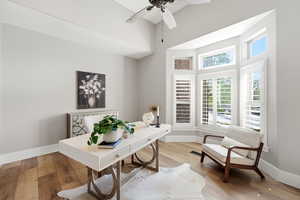 Home office featuring wood-type flooring, a high ceiling, and ceiling fan