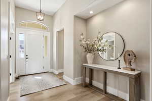 Entryway featuring light wood-type flooring and suspended lighting