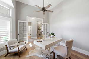 Office with light wood finished floors, vaulted ceiling, and a ceiling fan