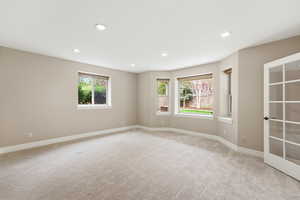 Unfurnished room with healthy amount of natural light, light carpet, and recessed lighting