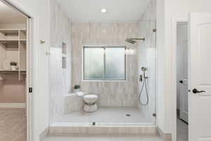 Bathroom featuring a walk in closet, tiled shower, and light tile patterned floors