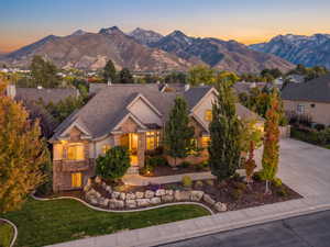 Craftsman inspired home featuring stone siding, a mountain view, concrete driveway, a front lawn, and stucco siding