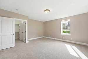 Unfurnished bedroom with a spacious closet and light carpet