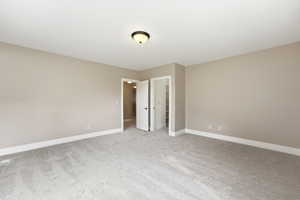 Unfurnished bedroom with a walk in closet and light carpet
