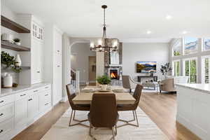 Dining space featuring a stone fireplace, light wood-type flooring, hanging lights, and arched walkways