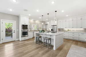 Kitchen featuring a center island, tasteful backsplash, stainless steel appliances, a kitchen bar, and decorative light fixtures