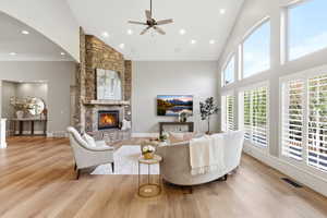 Living area with light wood-style flooring, vaulted ceiling, ceiling fan, a fireplace, and recessed lighting
