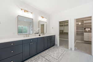 Bathroom with double vanity, a walk in closet, a shower stall, and light carpet
