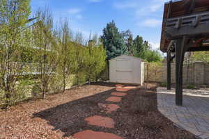 Fenced backyard featuring a storage shed