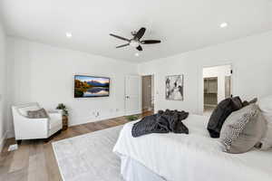Bedroom with a walk in closet, a ceiling fan, wood finished floors, and recessed lighting