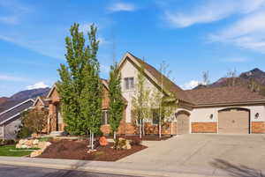 View of front of home featuring a mountain view, a garage, stone siding, stucco siding, and concrete driveway
