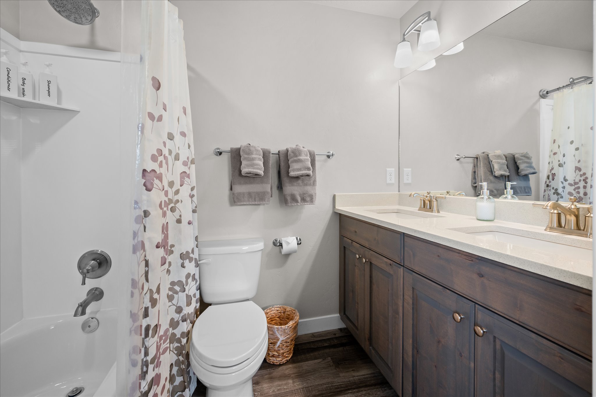 Full bath featuring double vanity, dark wood-style flooring, and shower / tub combo